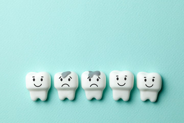 Healthy white teeth are smiling and tooth with caries is sad on green mint background. Copy space...