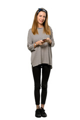 A full-length shot of a Young woman with headscarf sending a message with the mobile over isolated white background