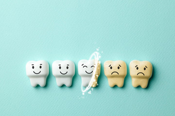 Teeth whitening. Healthy white teeth are smiling and yellow from cigarettes and sad coffee on green mint background. Copy space for text.