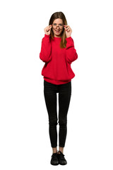 Fototapeta premium A full-length shot of a Young woman with red sweater with glasses and surprised over isolated white background