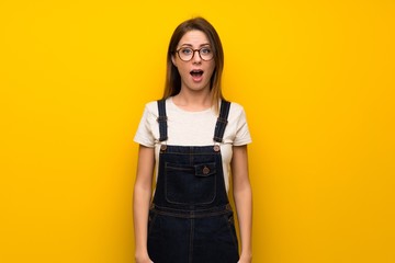 Woman over yellow wall with surprise facial expression