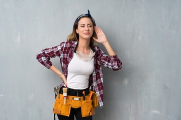 Craftsmen or electrician woman listening to something by putting hand on the ear