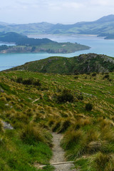 Foot path leading from mountain peak into valley and bay in distance