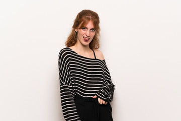 Fototapeta premium Young redhead woman over white wall showing tongue at the camera having funny look