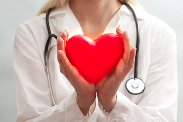 Female doctor with the stethoscope holding heart