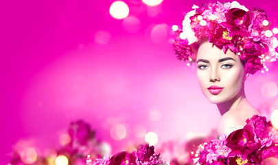Flowers hairstyle. Beauty model girl with pink peony flowers wreath over purple background