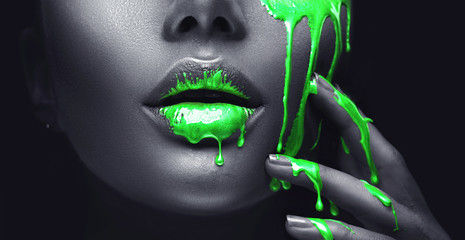 smudges drips from the face lips and hand, green liquid drops on beautiful model girl's mouth, creative abstract makeup. Beauty woman face