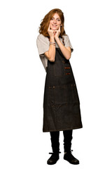Fototapeta premium A full-length shot of a Young redhead woman with apron smiling with a happy and pleasant expression over isolated white background