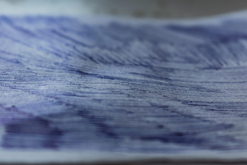 A sheet of white paper with painted dirty strokes, a blue ballpoint pen. Blurred background, shallow depth of field. Drawn record. Incomprehensible scribbles. The texture of an ordinary sheet of torn 