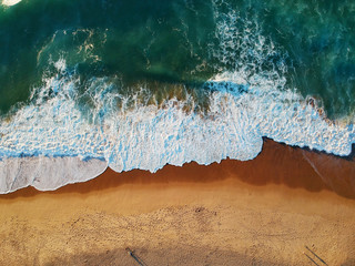Fototapeta na wymiar Aerial view of sandy beach with waves and clear ocean water. Drone phot
