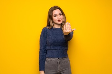 Teenager girl over yellow wall inviting to come with hand. Happy that you came