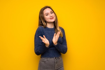 Teenager girl over yellow wall applauding after presentation in a conference