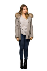 A full-length shot of a Teenager girl with coat is a little bit nervous and scared pressing the teeth on isolated white background