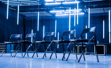 Metal chairs aligned for meeting in  modern business space illuminated with neon lights