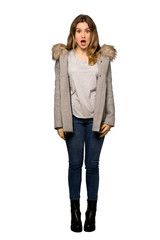 A full-length shot of a Teenager girl with coat with surprise and shocked facial expression on isolated white background