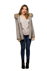 A full-length shot of a Teenager girl with coat showing tongue at the camera having funny look on isolated white background