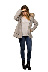 A full-length shot of a Teenager girl with coat looking far away with hand to look something on isolated white background