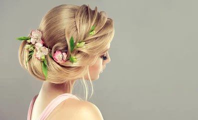  Mooi modelmeisje met elegant kapsel en roze bloemen in een vlecht. Vrouw met mode lente haren. © Sofia Zhuravetc