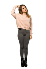 A full-length shot of a Teenager girl with pink sweater having doubts while scratching head over isolated white background