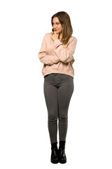 A full-length shot of a Teenager girl with pink sweater looking to the side over isolated white background