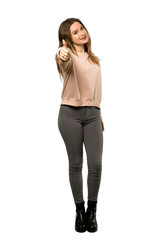 A full-length shot of a Teenager girl with pink sweater with thumbs up because something good has happened over isolated white background