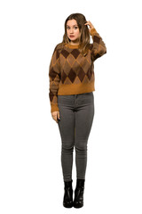A full-length shot of a Teenager girl with brown sweater having doubts while scratching head over isolated white background