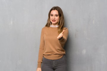 Teenager girl over textured wall shaking hands for closing a good deal
