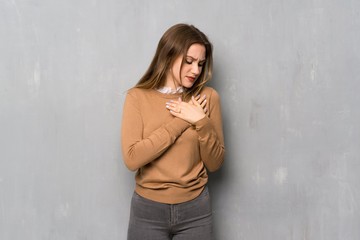 Teenager girl over textured wall having a pain in the heart