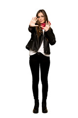 Fototapeta premium Full-length shot of Young woman with leather jacket is a little bit nervous and scared stretching hands to the front on isolated white background