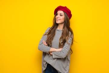 Girl with french style over yellow wall keeping the arms crossed while smiling