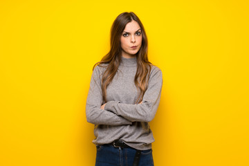 Young woman over yellow wall feeling upset