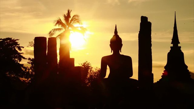 Time Lapse Sunset Silhouette buddha image Wat Mahathat Sukhothai temple Thailand pan left to right 