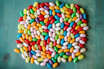 Jelly candy beans on blue wooden background. Close up view of heap of candy beans. 