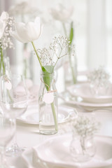 Happy Easter! Decor and table setting of the Easter table with white tulips and dishes of white color.