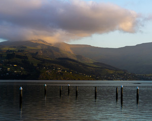 Clouds touching mountain peak during sunset with colorful reflections on the water
