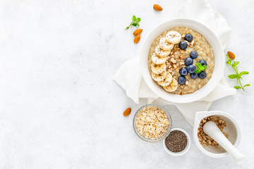 Healthy vegetarian food, oatmeal with fresh blueberry, banana, almond nuts and chia seeds for breakfast, view from above