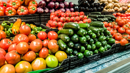 Cucumbers, onions, tomatoes and other vegetables are on the counter of the supermarket