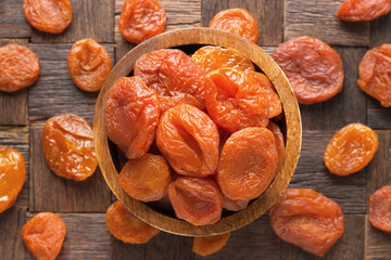 natural dried apricots in wooden bowl, top view.