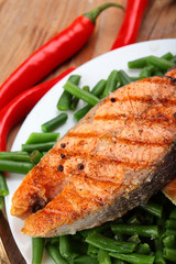 Salmon steak grilled on chives beans .Sea salt.On wooden table.Chilli pepper.Closeup.