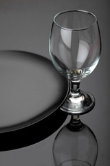 Black matte plate amd empty beer glass.On miroor surface.Dishes