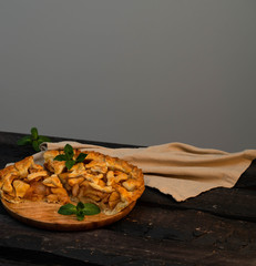 homemade apple pie on a wooden plate, on a rustic dark wooden backdrop