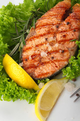 Salmon steak grilled with lemon.Sea salt.On leaf of salad.