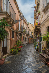 Fototapeta na wymiar Narrow typical italian street in the ancient Ortigia island, Syracuse, Sicily, Italy