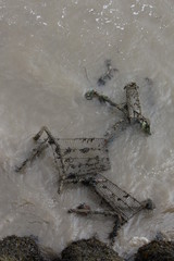 A photograph of discarded shopping trolleys in the ocean.  Murky water, environment pollution concept
