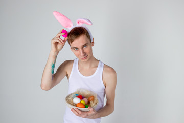 Handsome guy with bunny ears holding basket with eggs. Happy Easter concept