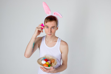 Obraz na płótnie Canvas Handsome guy with bunny ears holding basket with eggs. Happy Easter concept