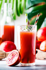 Summer juice or non-alcoholic refreshing healthy cocktail or drink from freshly squeezed red Sicilian orange, bright light table background. Selective focus