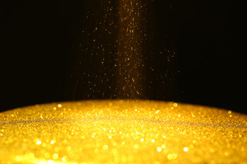 Gold powder with glitter lights on black background with copy space