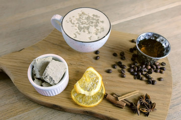 Cup of coffee with halva served on a tray with honey and coffee beans.
