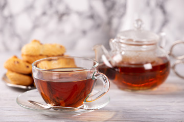 transparent teapot and cup of hot tea